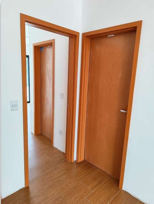 Corredor com portas de madeira e batentes alaranjados instaladas