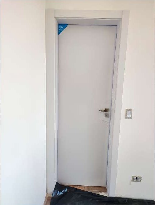 Porta branca com batente cinza instalada, ainda com a película de proteção