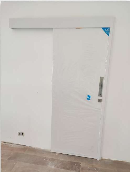Porta de correr branca com trilho aparente e puxador