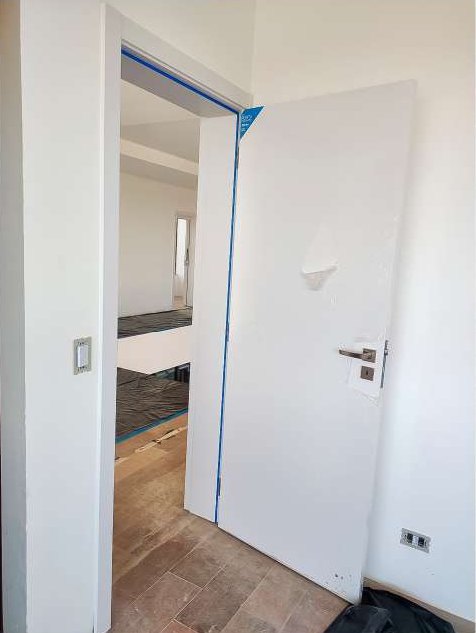 Porta branca aberta com maçaneta e fechadura instalada