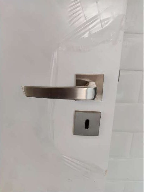 Detalhe da maçaneta e da fechadura em porta branca